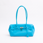 A bright turquoise blue leather handbag with double top handles, a front flap, and a silver-tone turn-lock closure,